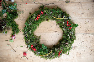 Handmade moss wreath with holly berries, twigs and pine cones