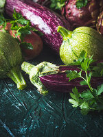 Purple and green vegetables - aubergines, red potatoes, chicory, artichokes and zucchini