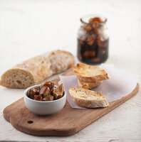 White bowl with preserved garlic and balsamic vinegar on wooden table with some slices of bread