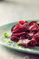 Beet chips with basil and sea salt, on blue plate