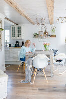 Frau sitzt am Holztisch im Esszimmer im modernen Landhausstil