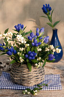 Closed Gentiana with snowberries as a bouquet in basket vase