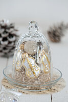 White and gold Christmas ornaments under a bell jar