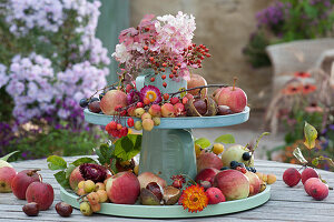 Selbstgebaute Etagere aus Haushaltsutensilien herbstlich dekoriert mit Äpfeln, Zieräpfeln, Hagebutten, Kastanien, Strohblumen und Hortensienblüten