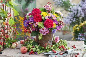 Herbststrauß mit Rosen, Astern, Chrysanthemen, Hopfen, Hagebutten und Sommeraster im Hopfenkranz