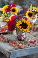 Herbstliche Tischdeko mit Zieräpfeln, Sonnenblumen und Rosen