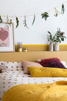 Garland of fairy lights and various twigs above bed