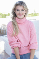 Junge blonde Frau im rosa Rollkragenpullover