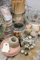 Gläser mit Bastelmaterialien wie Eier, Holzstäbe, Tontöpfe und Schnur