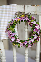 Spring wreath of hyacinth florets, waxflowers, mimosa and box tied to chair backrest