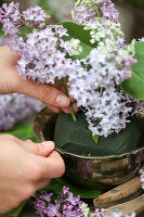 Arranging a bouquet of lilac and cow parsley in florists' foam