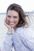 A young brunette woman by the sea wearing a knitted jumper