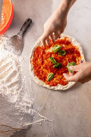 Basil leaves being added to a pizza