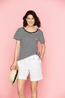 A brunette woman wearing a straw hat, a striped t-shirt and white shorts