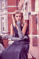 A young blonde woman wearing a denim dress and long gloves