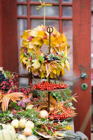 three tiered dessert stand with an autumn wreath of autumn leaves and berries