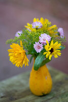 Kleiner Strauß aus Ringelblumen, Fenchelblüten und Margeriten in Zierkürbis als Vase