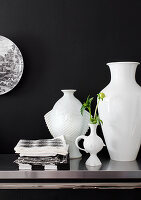 White vases in different shapes against black wall