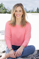 A young blonde woman wearing a pink top and jeans