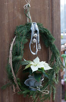 Christmas door wreath made of spruce branches and clematis tendrils with white poinsettia wrapped in felt