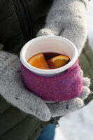 Woman with gloves holding cup with hot punch wrapped in felt