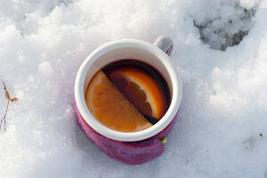 Tasse mit heißem Punsch umwickelt mit Filz im Schnee