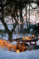 Hanging lanterns on a tree over a settable in a snowy garden