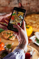 A girl holds a phone in her hands on the background of a table with food