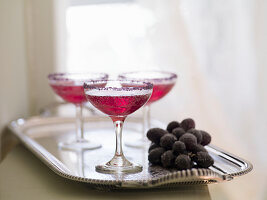 Red cocktails with sugared grapes on a silver tray
