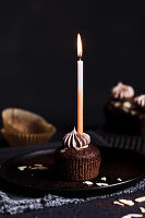 A chocolate cupcake with a lit candle