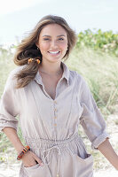 A young, long-haired woman wearing a beige linen blouse and shorts