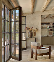 Armchairs in front of open patio doors in living room with sand colored walls and exposed wooden beams