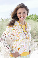 A young woman with long hair wearing a yellow t-shirt and a white crocheted jumper