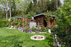 Schrebergarten mit Gartenhaus, Gerätehaus, Staudenbeet, Rasen und Feuerplatz