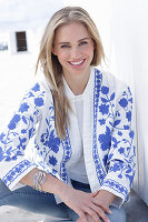 A long-haired blonde woman wearing jeans and a blue-and-white jacket