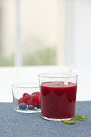 Strawberry and black current smoothie near luminous window inside Tupperware