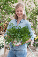 A woman holding a colander planted with parsley