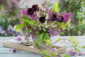 Spring bouquet of lilacs, black tulips, lilies of the valley and climbing cucumber