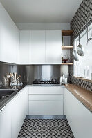 Galley kitchen with white cupboards and stainless steel splashback