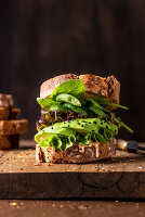 Sandwich with peanut butter, avocado, salad, cucumber and spinach leaves