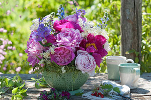 Arrangement of peonies, cranesbills, elderflowers and common bugloss in colander