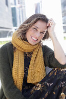 A woman wearing a yellow knitted scarf and a green knitted coat