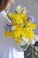 Woman carrying spring bouquet with daffodils, tulips, scabiosa