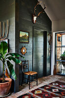 Green-painted wood panelling and colourful rug on reused floor tiles in hall