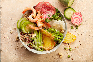 A bowl with edamame, radishes, yellow beets, chioggia beets and prawns