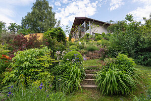 Sommerlicher Garten vor Haus in Hanglage