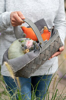 Woman brings gift basket with pumpkins 'Hungarian Blue' and Hokkaido pumpkin, rose blossom and man litter