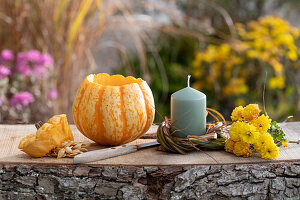 Hollowed pumpkin as pumpkin vase for autumn bouquet with Chrysanthemums, candle in grass wreath