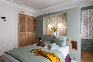 Bedroom with patterned wallpaper, wooden wardrobe and green bed linen