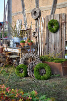Zinc house ornaments, terracotta pots, willow wreaths and moss wreaths on and around old table